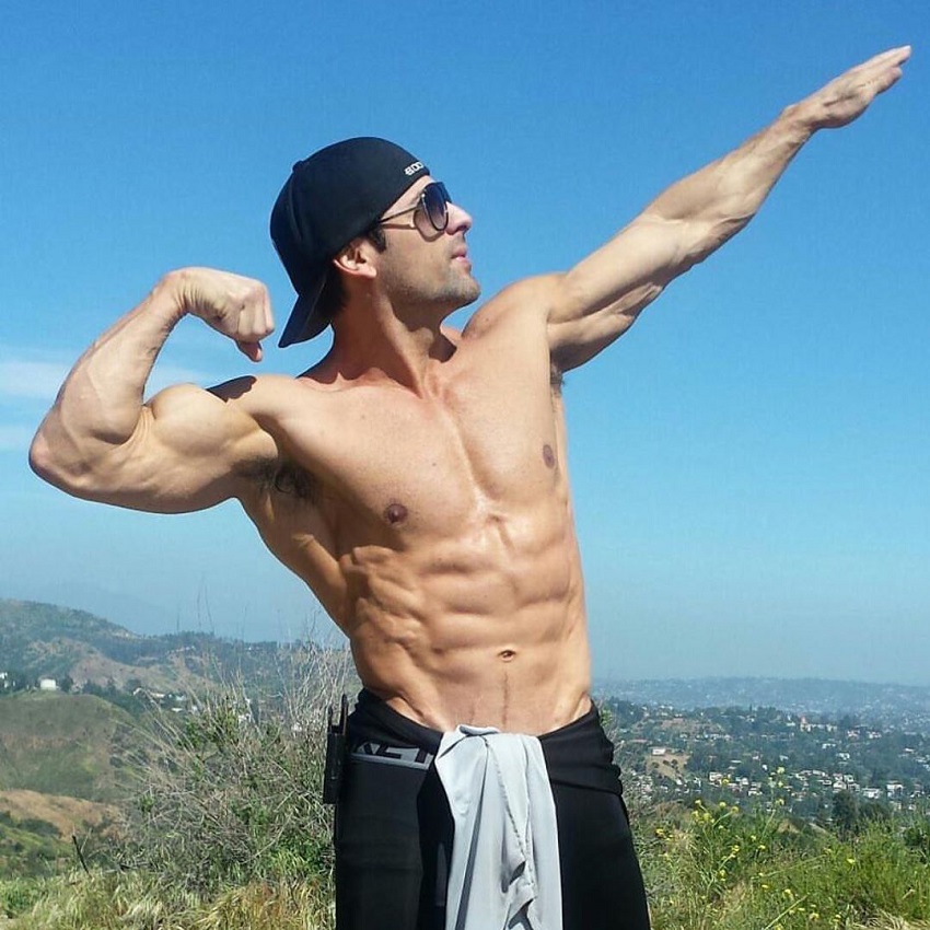 TJ Hoban striking a bodybuilding pose shirtless outdoors