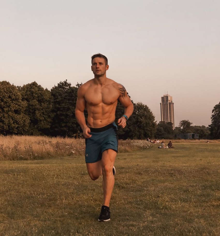 Alex Crockford running shirtless through the green field at dusk