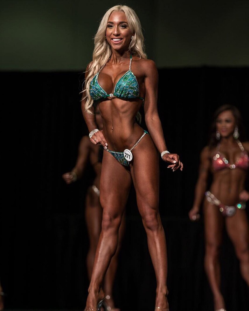 Cath Bastien posing on the stage in a green bikini outfit