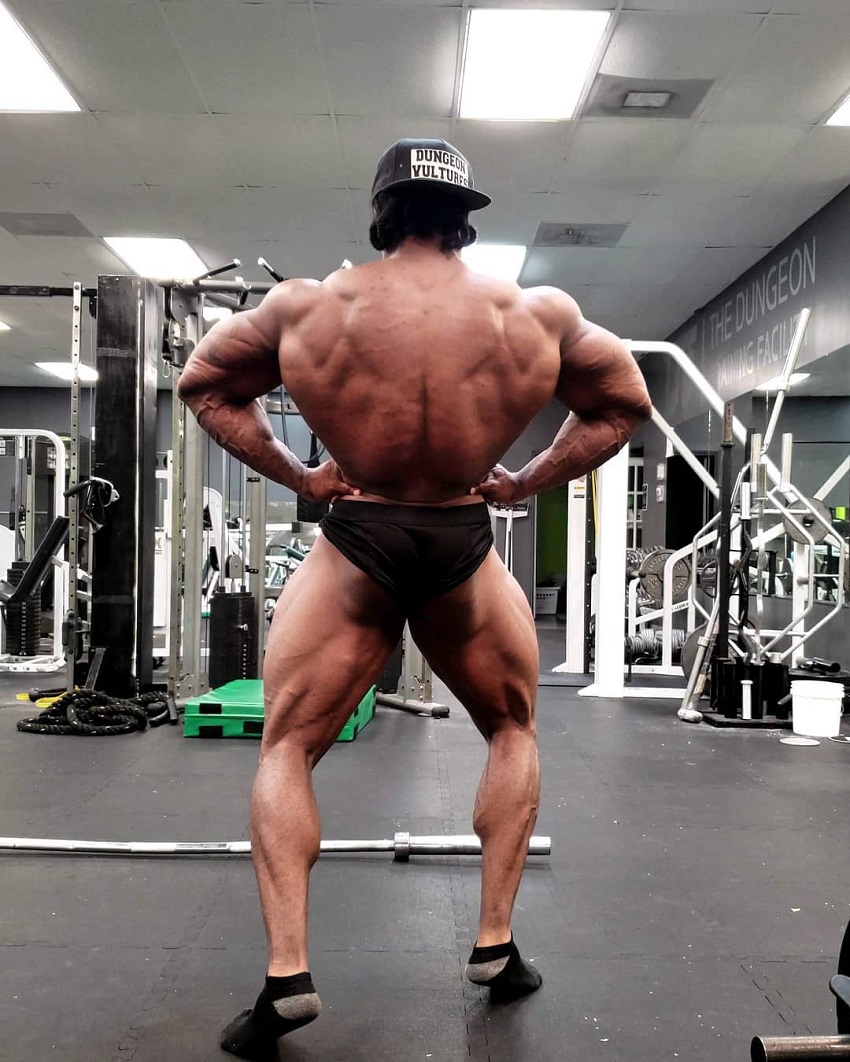 Rickey Moten doing a rear lat spread shirtless in a gym