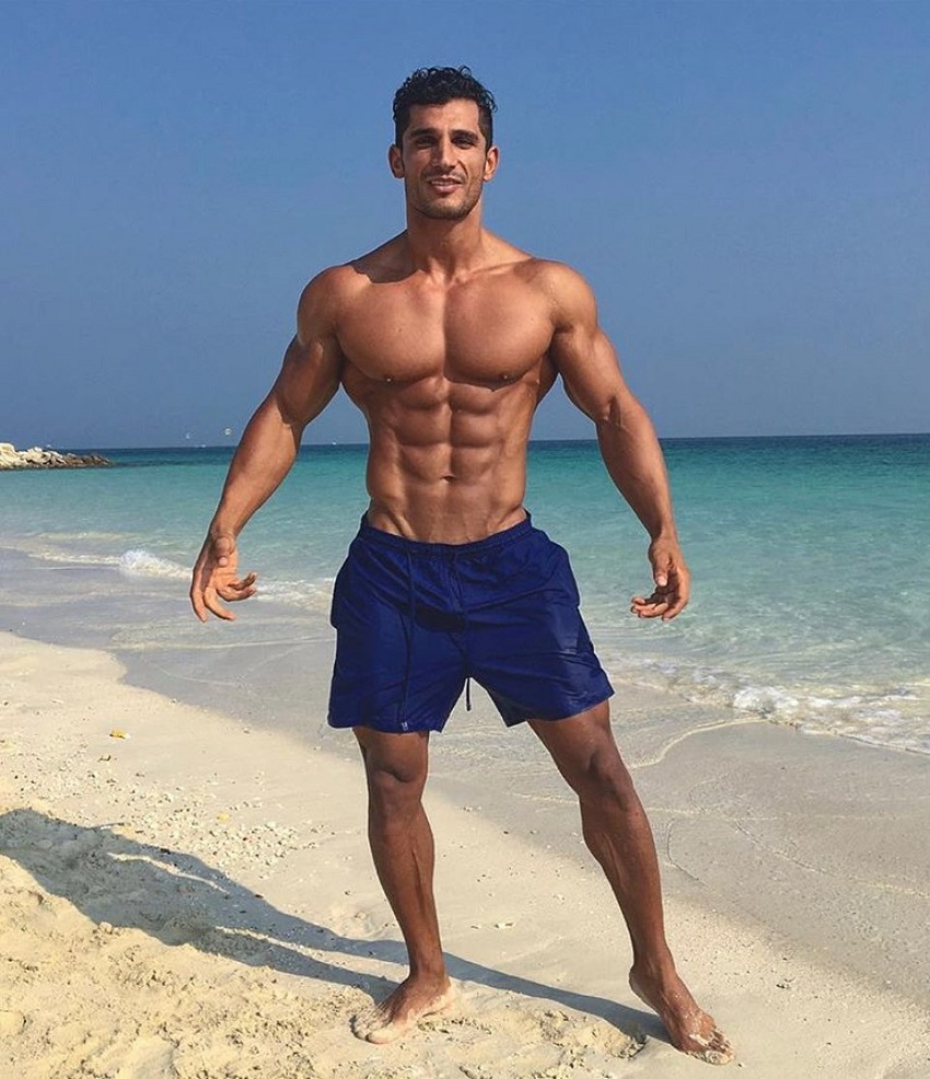 Akbar Sarbaz flexing shirtless on a beach