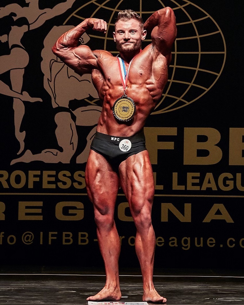 Luke Hulme posing with a medal around his neck in a bodybuilding show