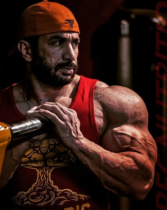 Mojtaba Notarki posing next to a squat bar, looking huge