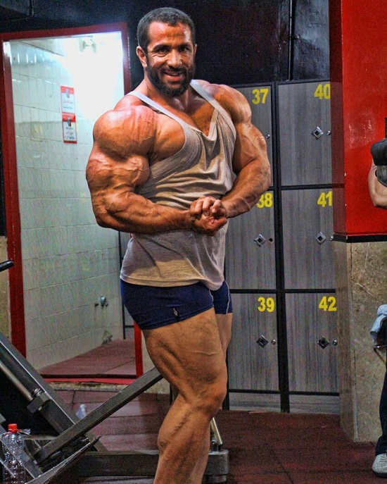 Mojtaba Notarki doing a side chest flex, looking ripped and swole