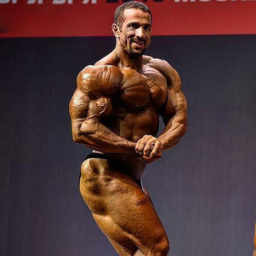 Mojtaba Notarki flexing side chest on the bodybuilding stage