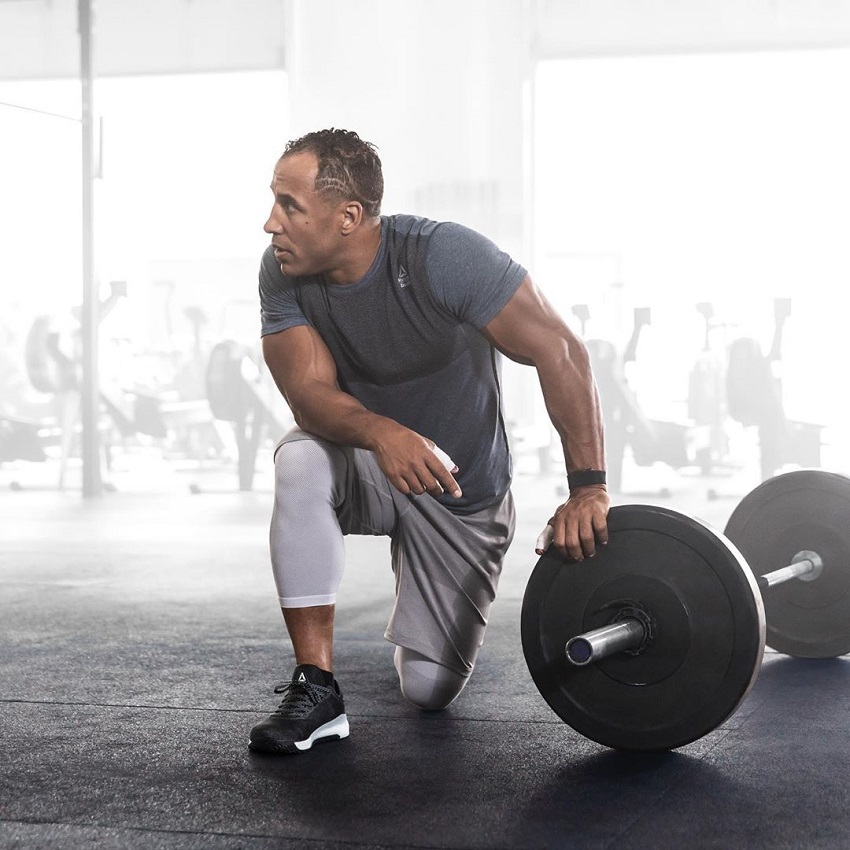 Neal Maddox leaning on a barbell in the gym