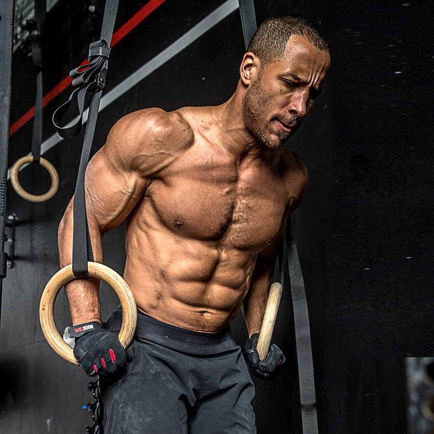 Neal Maddox training shirtless on rings, looking ripped and muscular