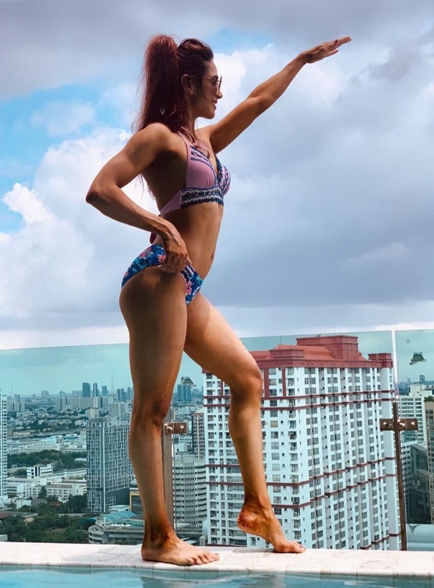 Vaishali Bhoir posing in a bikini on top of a tall building overlooking a city and a sea
