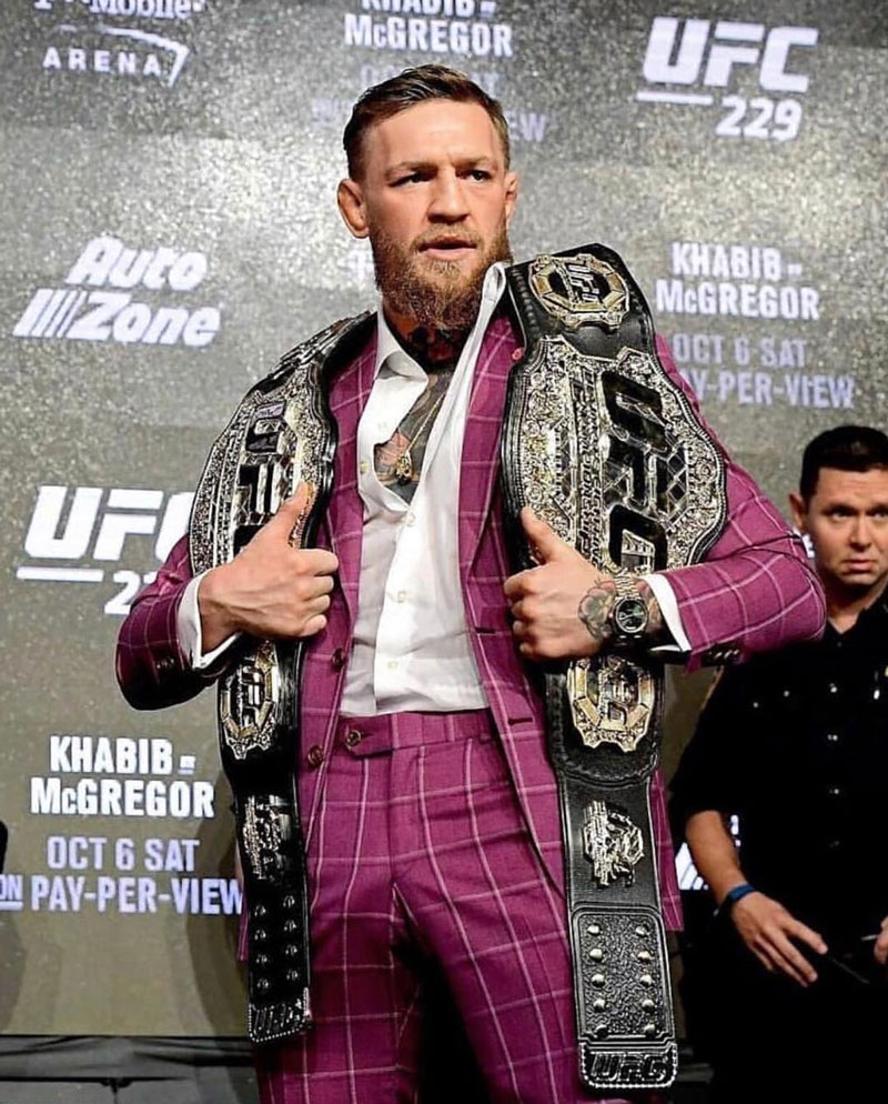 Conor McGregor standing with two belts